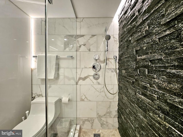 bathroom with toilet and a tile shower
