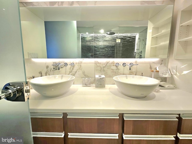 bathroom featuring a sink, a shower stall, backsplash, and double vanity