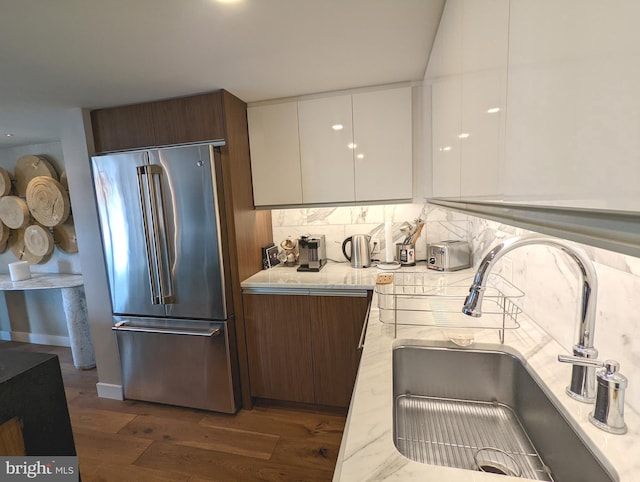 kitchen featuring tasteful backsplash, sink, white cabinets, high quality fridge, and dark hardwood / wood-style flooring