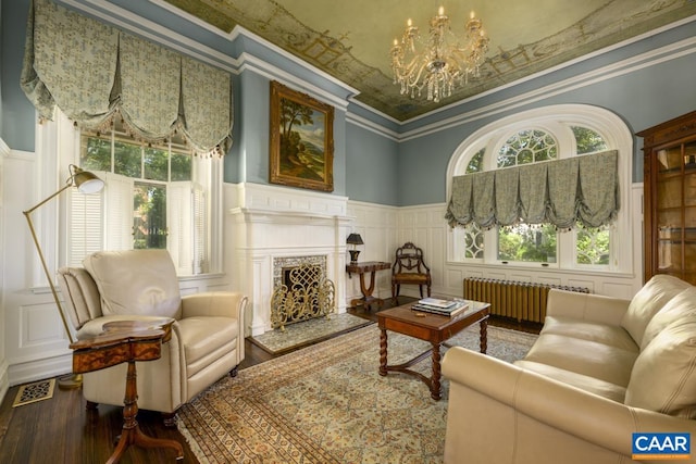 sitting room featuring radiator, ornamental molding, hardwood / wood-style flooring, a high ceiling, and an inviting chandelier