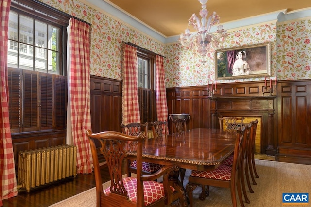 dining area with hardwood / wood-style floors, a chandelier, ornamental molding, and radiator heating unit