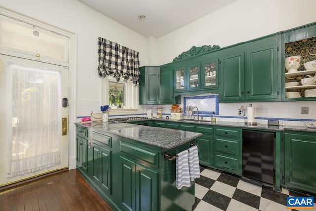 kitchen with dark wood-type flooring, sink, decorative backsplash, green cabinets, and dark stone countertops