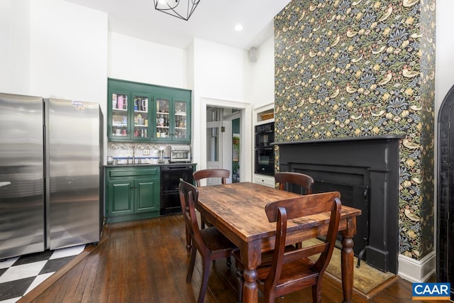 dining area with bar, a towering ceiling, and dark hardwood / wood-style flooring