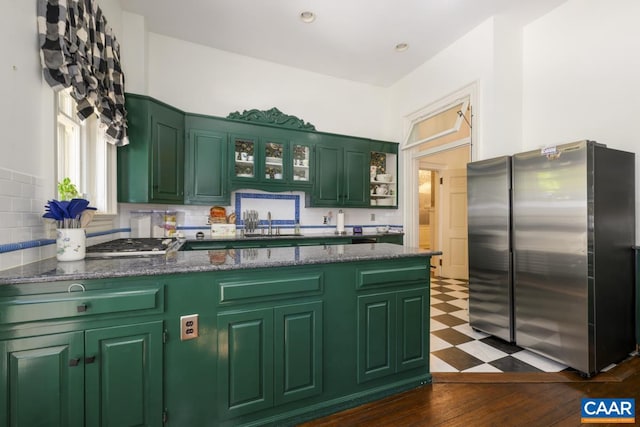 kitchen with green cabinetry, appliances with stainless steel finishes, dark wood-type flooring, and tasteful backsplash