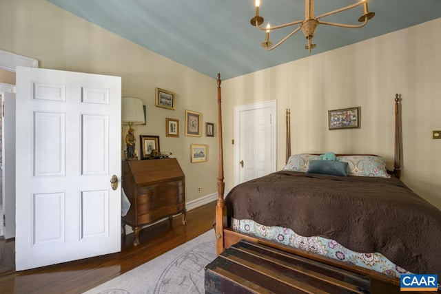 bedroom with an inviting chandelier, vaulted ceiling, and dark hardwood / wood-style flooring