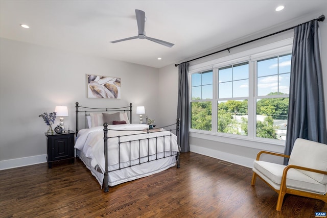 bedroom with ceiling fan, dark wood-type flooring, and multiple windows