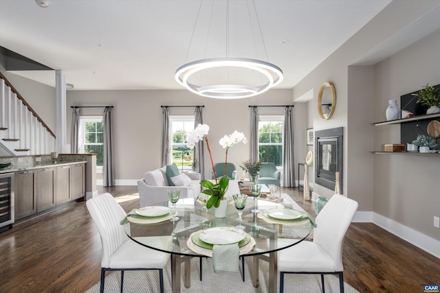 dining room with a notable chandelier, beverage cooler, and dark hardwood / wood-style flooring