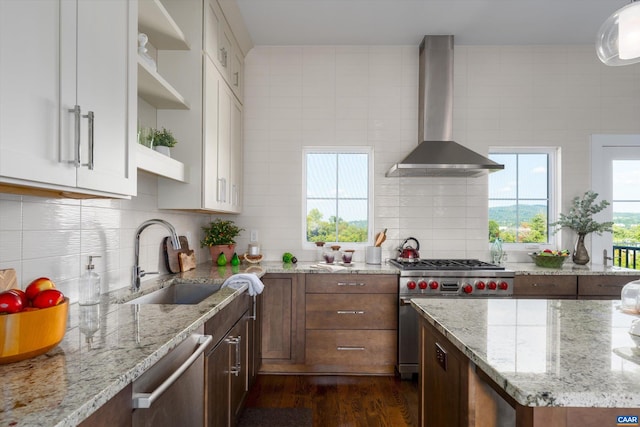 kitchen with wall chimney exhaust hood, white cabinets, appliances with stainless steel finishes, and dark wood-type flooring