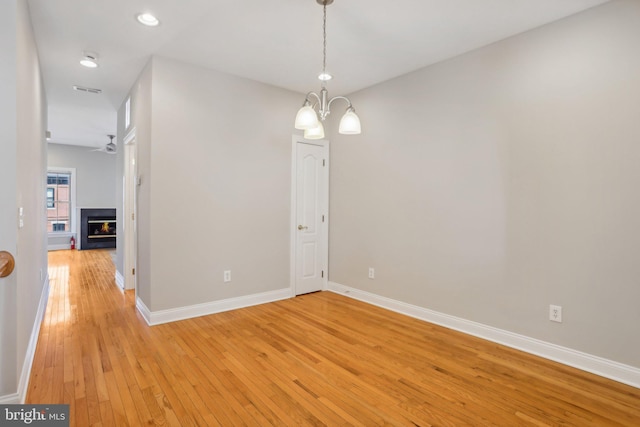 unfurnished room with light hardwood / wood-style flooring and ceiling fan with notable chandelier