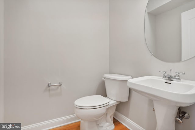 bathroom featuring wood-type flooring, toilet, and sink