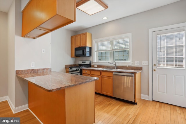 kitchen featuring kitchen peninsula, light hardwood / wood-style flooring, stainless steel appliances, and a wealth of natural light