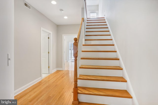 stairway featuring a healthy amount of sunlight and hardwood / wood-style floors