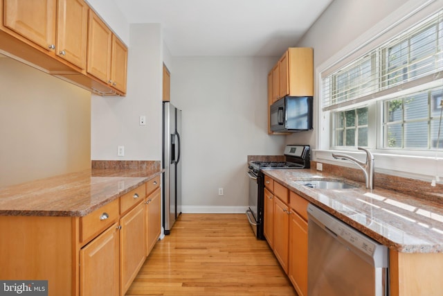 kitchen featuring light wood-type flooring, sink, kitchen peninsula, black appliances, and light stone countertops