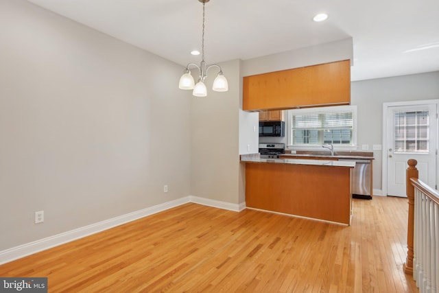 kitchen featuring light hardwood / wood-style floors, kitchen peninsula, pendant lighting, stainless steel appliances, and a chandelier