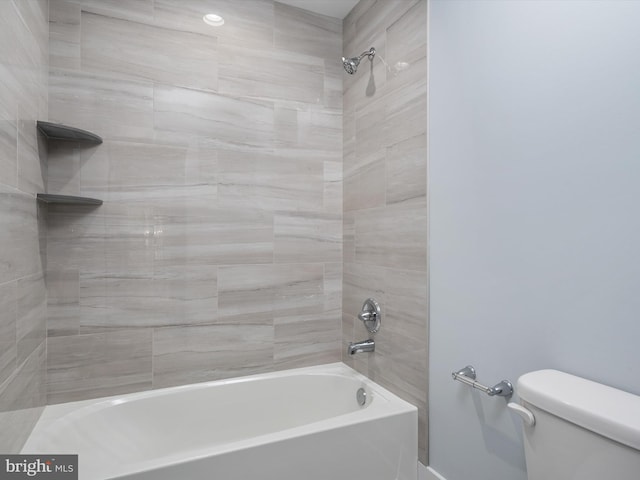 bathroom featuring tiled shower / bath combo and toilet