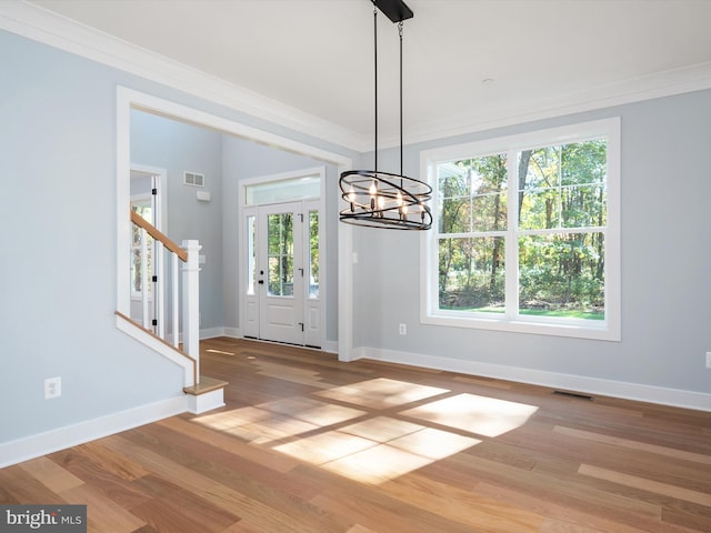 unfurnished dining area featuring a wealth of natural light, crown molding, light hardwood / wood-style floors, and a chandelier