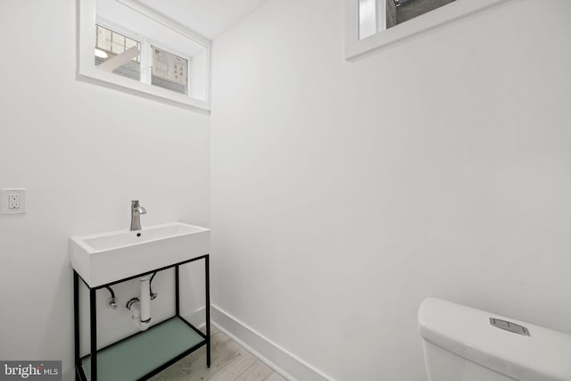 bathroom featuring wood-type flooring, toilet, sink, and a wealth of natural light