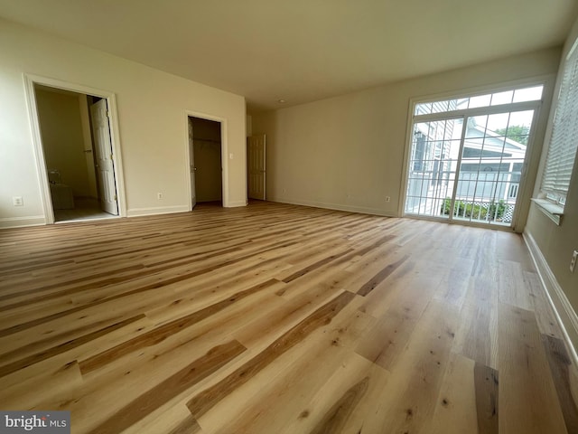 unfurnished bedroom featuring light hardwood / wood-style flooring, ensuite bath, a closet, and access to outside