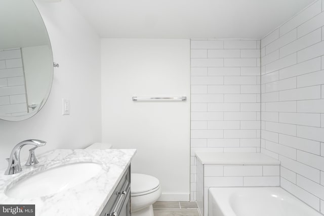 bathroom featuring vanity, a tub to relax in, toilet, and hardwood / wood-style flooring