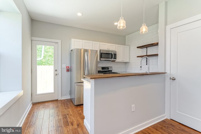 kitchen with light hardwood / wood-style floors, stainless steel appliances, kitchen peninsula, and white cabinetry