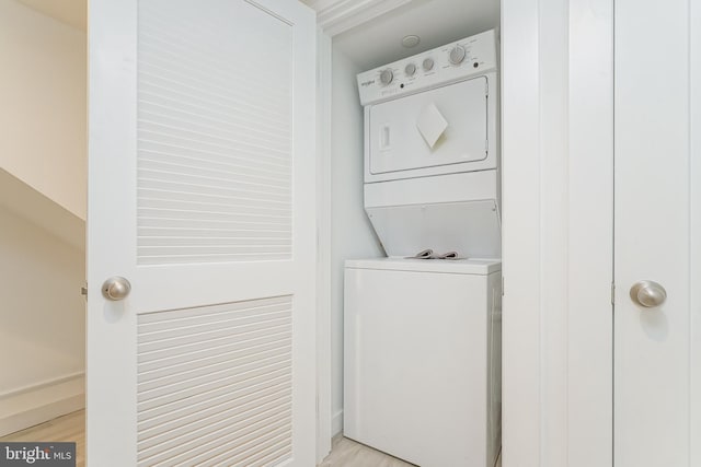 laundry area with stacked washer / drying machine and light wood-type flooring