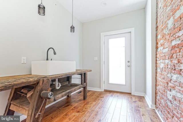 interior space with brick wall, sink, and light hardwood / wood-style floors