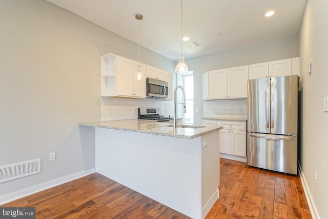 kitchen with wood-type flooring, kitchen peninsula, stainless steel appliances, and white cabinets