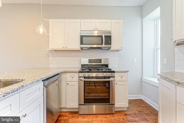 kitchen with white cabinets, decorative light fixtures, appliances with stainless steel finishes, hardwood / wood-style floors, and decorative backsplash