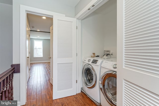 laundry room with washing machine and clothes dryer and hardwood / wood-style flooring