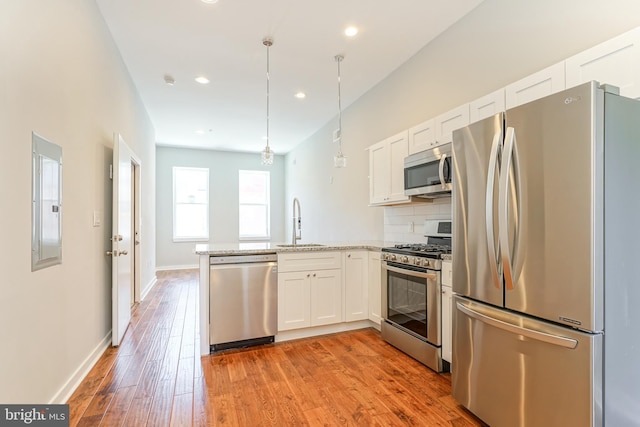 kitchen featuring appliances with stainless steel finishes, white cabinets, kitchen peninsula, light hardwood / wood-style flooring, and sink