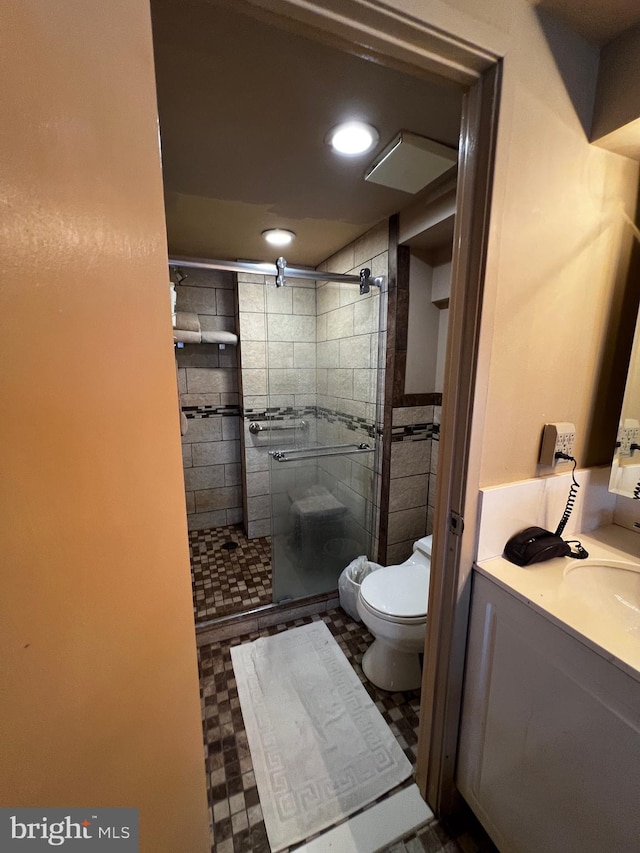 bathroom featuring tile patterned flooring, vanity, toilet, and a shower with door