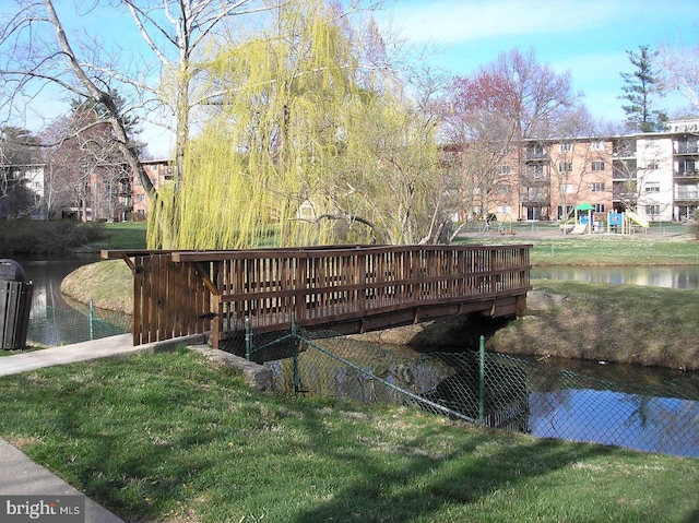 dock area featuring a playground, a lawn, and a water view