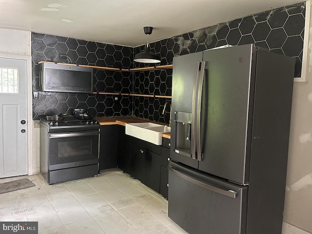 kitchen featuring decorative backsplash, stainless steel fridge, sink, and black range with gas cooktop