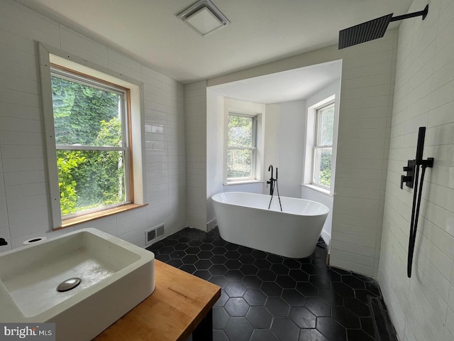 bathroom with plenty of natural light, tile walls, and sink