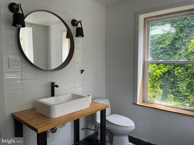 bathroom featuring toilet, sink, and tile walls