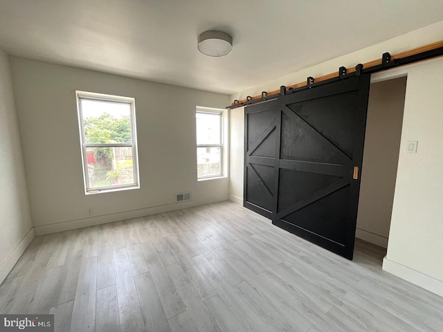 spare room featuring a barn door and light hardwood / wood-style floors