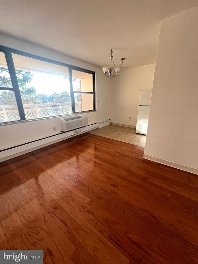 unfurnished room with light hardwood / wood-style floors, a notable chandelier, and a baseboard heating unit