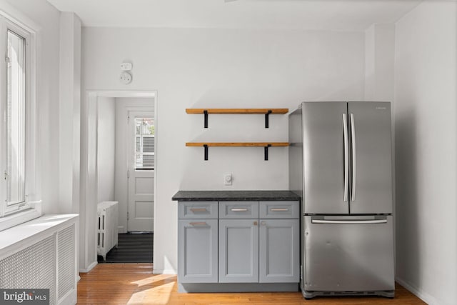 kitchen featuring radiator heating unit, gray cabinetry, light hardwood / wood-style flooring, and stainless steel refrigerator