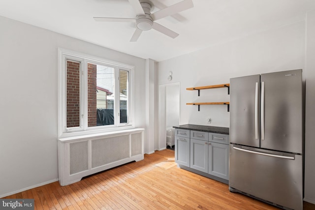 kitchen with stainless steel fridge, radiator, ceiling fan, and light hardwood / wood-style flooring