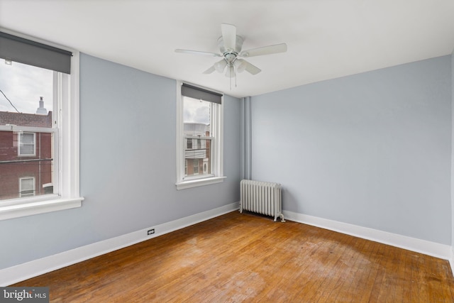 spare room with ceiling fan, light hardwood / wood-style floors, and radiator heating unit