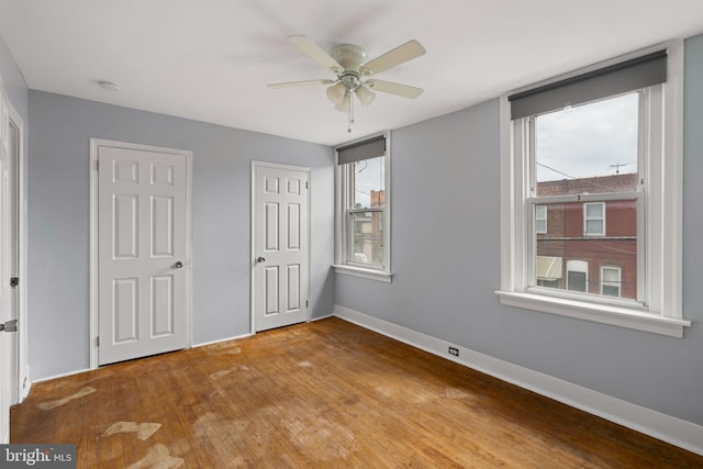 unfurnished bedroom with light wood-type flooring, two closets, and ceiling fan