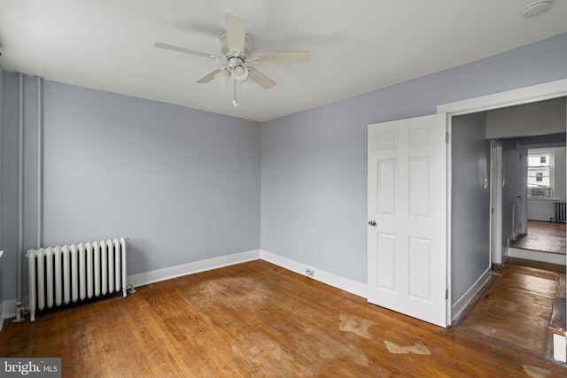 spare room with ceiling fan, radiator, and dark hardwood / wood-style floors