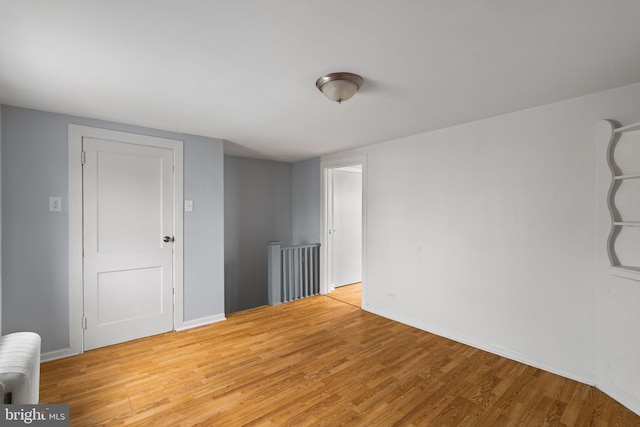 unfurnished room featuring light hardwood / wood-style flooring and radiator heating unit