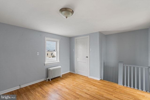 unfurnished bedroom featuring radiator, a closet, and hardwood / wood-style floors