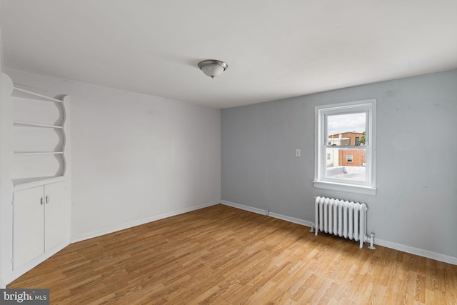 unfurnished room featuring light hardwood / wood-style floors and radiator heating unit