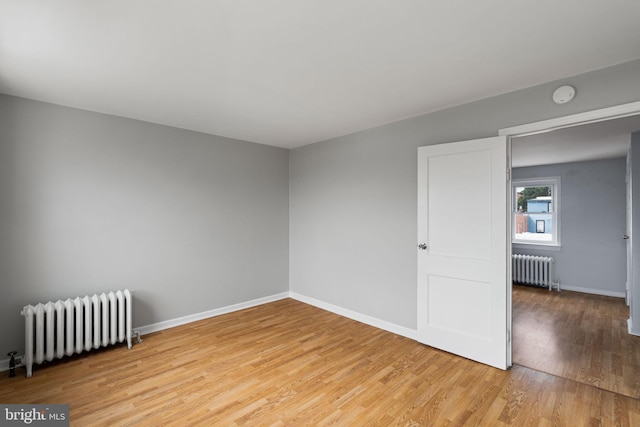 spare room with radiator heating unit and light wood-type flooring