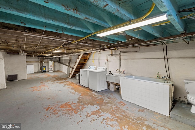 basement with water heater, washer and clothes dryer, and sink