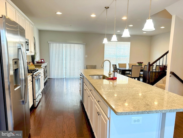 kitchen featuring sink, stainless steel appliances, an island with sink, pendant lighting, and white cabinets