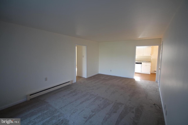 carpeted spare room featuring a baseboard heating unit