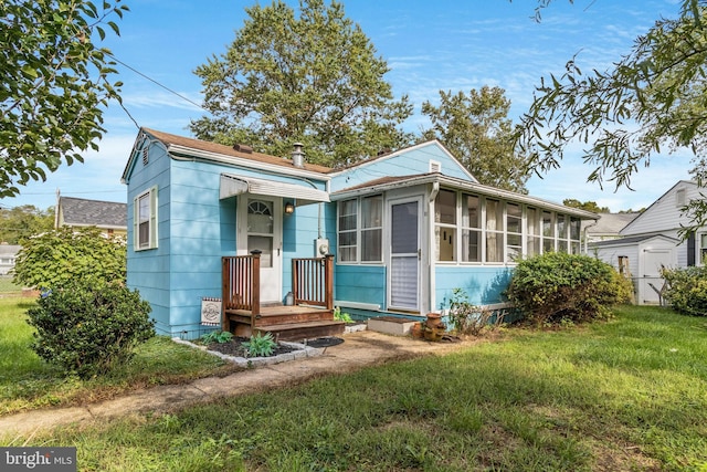 view of front of property featuring a sunroom and a front lawn